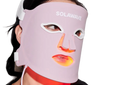Woman relaxing while wearing the Glow Retreat Pro LED face mask in a warm red glow